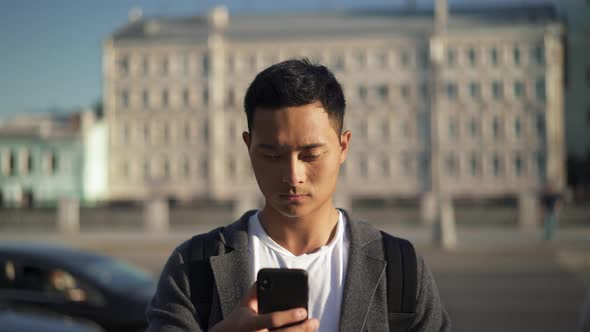 Left To Right Pan Real Time Shot of a Young Asian Man Leading a Correspondence on the Phone. Moscow