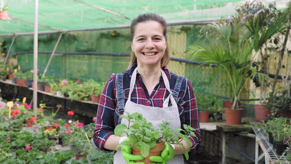 Happy woman working in flower garden shop