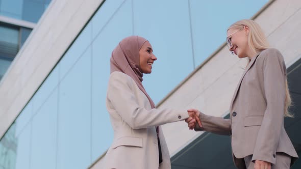 Happy Muslim Businesswoman Sales Manager in Hijab Shake Hand of Millennial Caucasian Lady Client