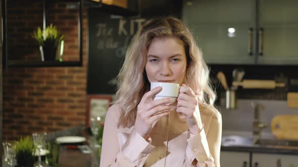 Portrait of beautiful successful woman drinking coffee in the evening in kitchen