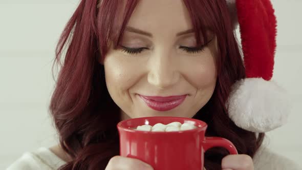 Woman smelling hot cup of cocoa and marshmallows