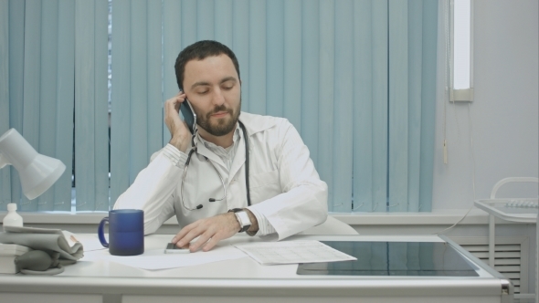 Male Doctor Speaking On Cellphone At Modern Hospital Indoors