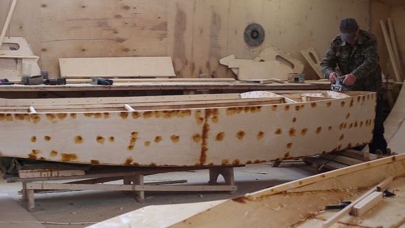 A Carpenter Polishes Details Wooden Boat at the Shipyard