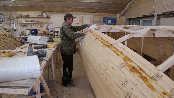 Carpenter Studies the Draft of the Boat at the Shipyard