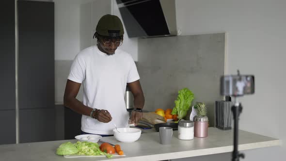African Man Standing in Kitchen Records on Cellphone New Food Videoblog in the Morning Slow Motion
