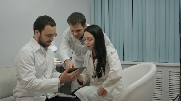 Team Of Doctors Watching Something Funny On Tablet Pc In a Medical Office