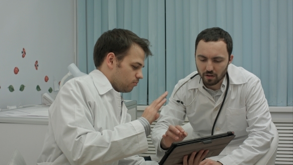 Male Doctors Watching On Tablet Pc And Discussing Results