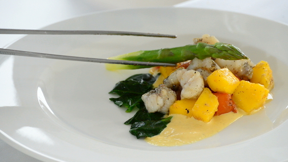 Chef Adding Pieces of Fish and Asparagus alt