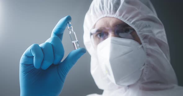 Closeup of Doctor in Protective Medical Uniform Nurse Wearing Face Mask Glasses and Gloves Holding