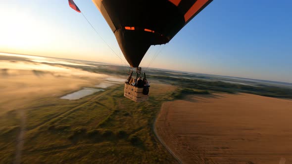 hot air ballon floating above sloping field at beautiful sunrise