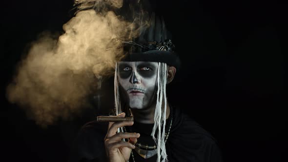 Sinister Man with Horrible Halloween Skeleton Makeup Smoking Cigar, Making Faces, Looking at Camera