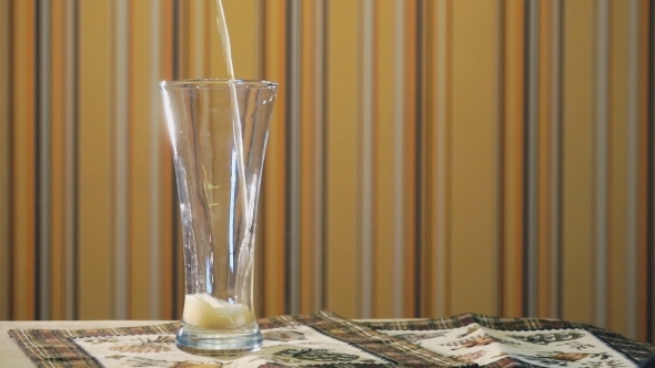 Jet of Light Beer Fills a Transparent Glass on The Table