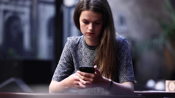 Upset Young Woman With Mobile Phone At Restaurant