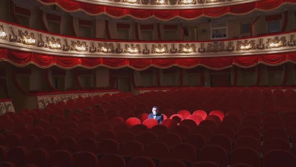 Rich man in mask in empty theater hall.