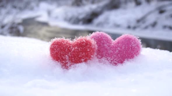 Red and Pink Woolen Hearts on White Snow on the River Shore in Winter