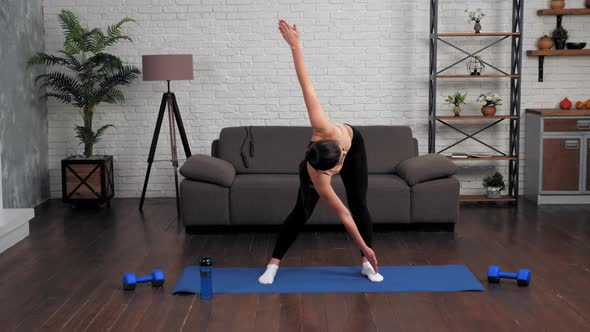 Young Fit Woman in Sportswear Doing Warmup Before Workout on Yoga Mat at Home