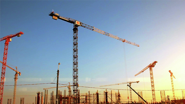 Cranes Working in Construction Site on Sunset