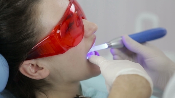 Female Patient Getting Treatment With Dental UV Light Equipment
