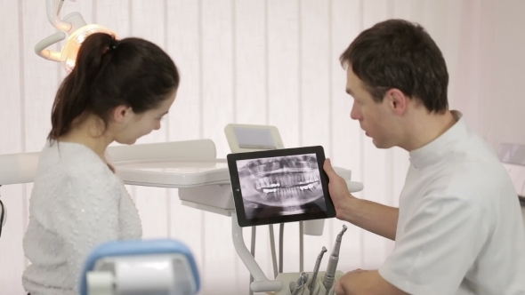 Dentist Shows A Patient X-Ray On The Tablet