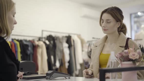 Portrait of Confident Gorgeous Woman Paying for Purchase with Credit Card and Taking Shopping Bag