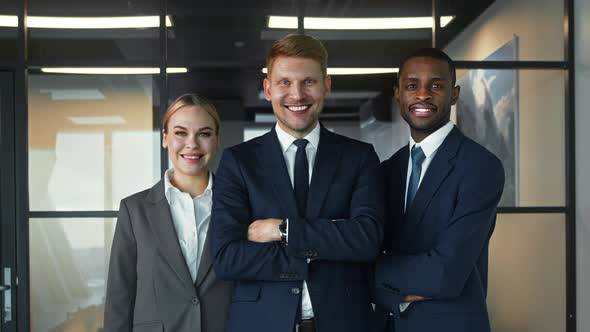 Smiling young people in business suits against the wall in the office