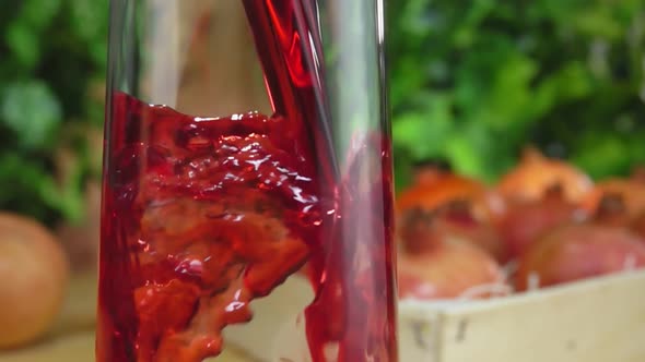 Closeup of Pomegranate Juice Poured in a Jug Next To Box Full of Pomegranates