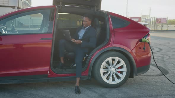 Confident Male Entrepreneur Sitting Inside His Luxury Red Car with Opened Door