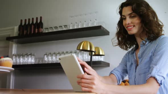 Smiling woman using digital tablet at counter