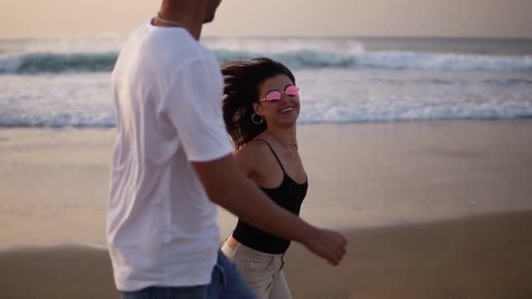 Vacation Couple in Sunglasses at Beach at Sunset Romantic Holding Hands Running Playfully