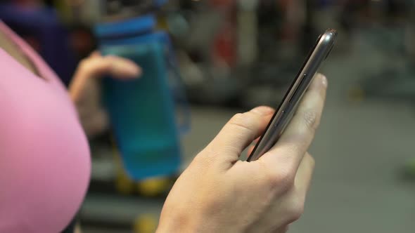 Girl Checking Information on Cellphone, Holding Water Bottle, Healthy Diet App