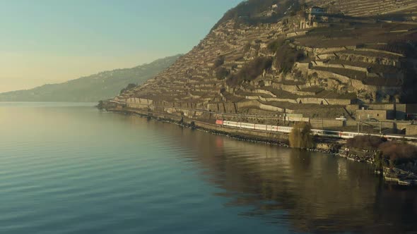 Passenger Train Goes Along Lake Geneva Shore at Sunset. Aerial View