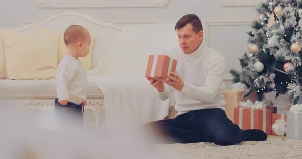 Happy Father Gives the Kid a Box with a Gift New Year Holidays