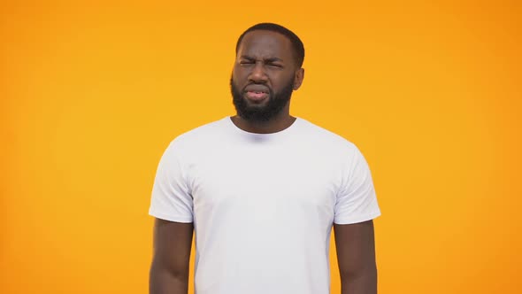 African American Man Showing Confused Reaction at Camera on Yellow Background