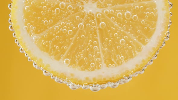 Lemon Slice in Carbonated Water on Yellow Background Fizzy Summer Drink Making Cocktail of Citrus