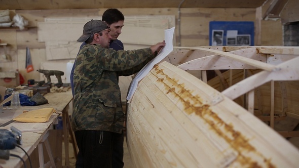 Carpenter Explains to a Colleague the Details of the Draft of the Boat at the Shipyard