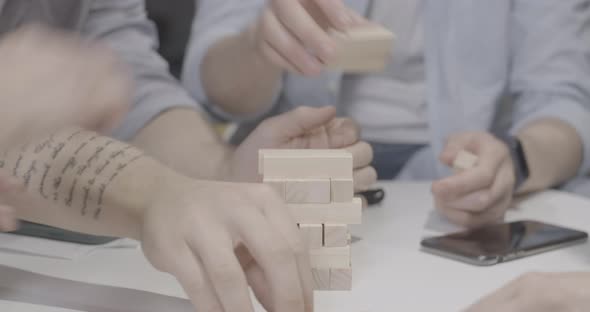 Male and Female Hands Building Jenga Tower on Table