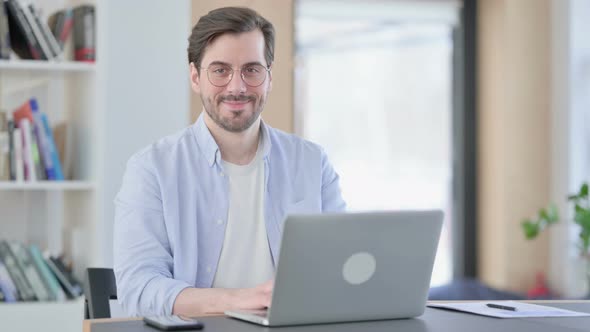 Man in Glasses with Laptop Smiling at Camera