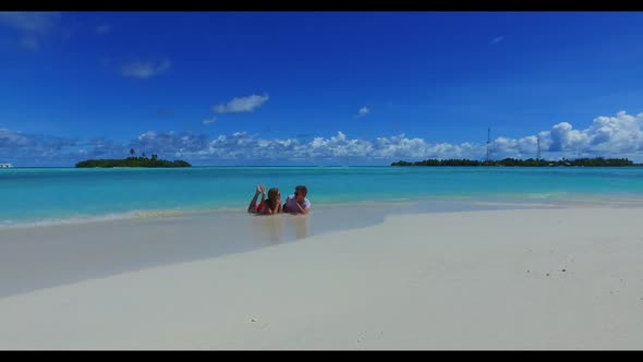 Two people happy together on relaxing bay beach voyage by blue lagoon and white sand background of t