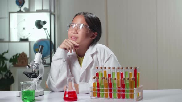 Young Scientist Girl Looking At Microscope And Thinking In Laboratory Experiment With Liquid