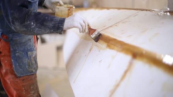 The Carpenter Seals the Joints of the Boat at the Shipyard alt