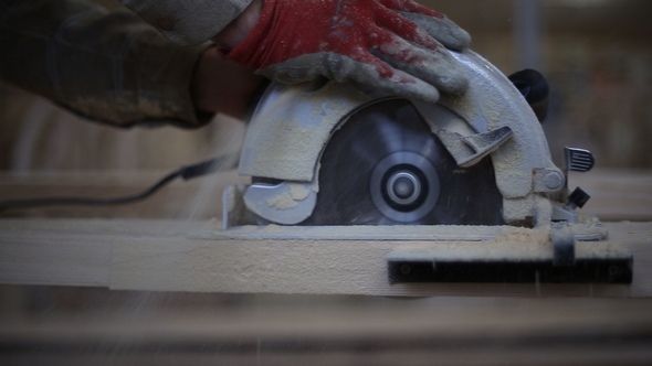 A Carpenter Saws Off a Board with a Disk Saw