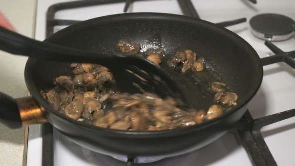 The Mix Of Mushrooms Is Fried In a Black Pan alt