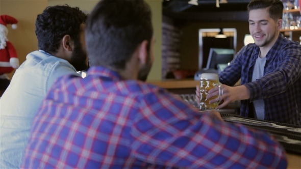 Friends Drinking Beer At Counter In Pub