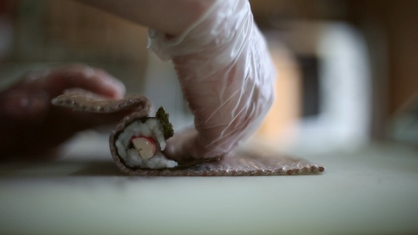 A Sushi Chef Prepares Rolls using a Bamboo Mat