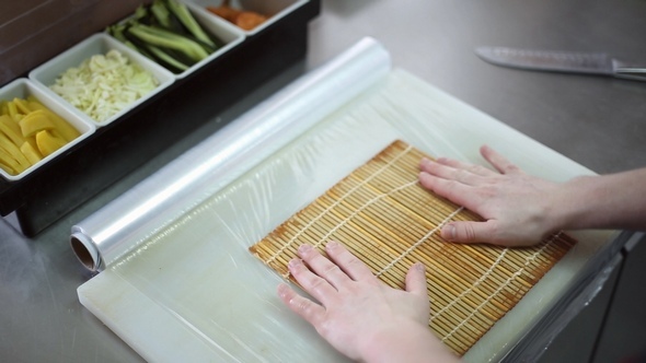 A Sushi Chef Prepares the Bamboo Mat to Tighten the Roll alt