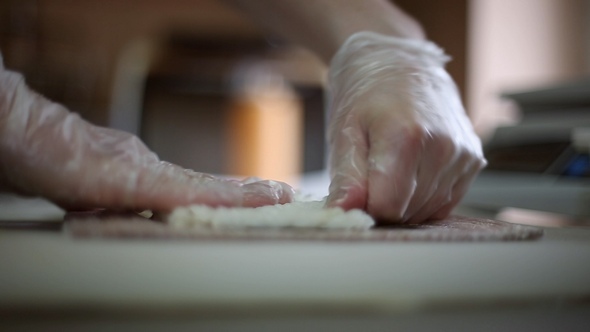 A Sushi Chef Prepares Rolls using a Bamboo Mat