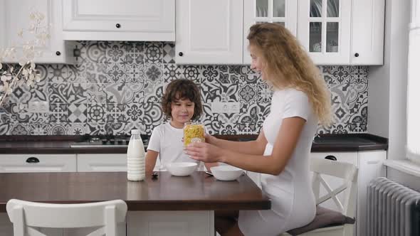 Charming Mother and Smiling Son which Sitting at the Kitchen Table