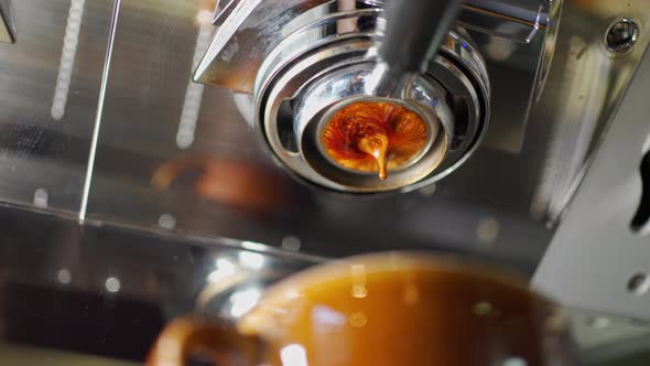 Beautiful Extraction of Espresso in a Thin Stream From the Naked Filter Holder Into a Brown Ceramic