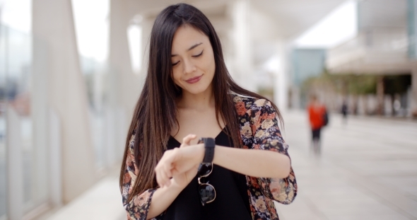 Young Woman Looking At The Time With a Smile