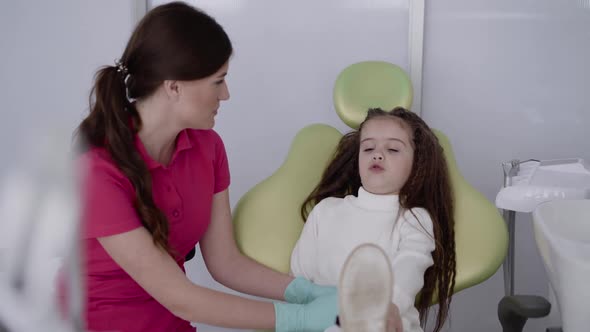 The Female Dentist Preparing a Child Patient Playfully for Dental Treatment